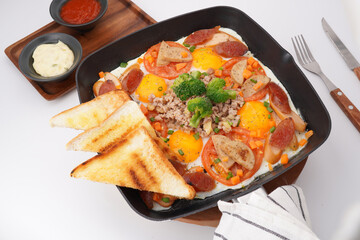Fast food breakfast, fried eggs in pan and vegetables