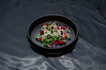 Ceramic bowl with black water with berry salad