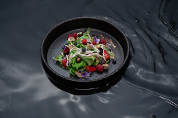 Ceramic bowl with black water with berry salad