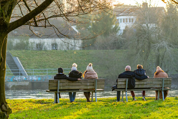 Menschen sitzen zum entspannen auf einer Bank an der Donau in Niederbayern
