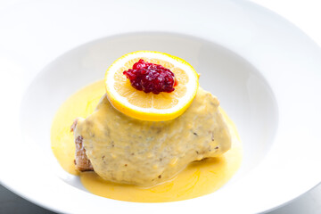 poultry meat with creamy sauce served with lemon and cranberries