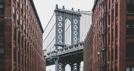 Obraz premium Red brick buildings with Brooklyn bridge sprouting between them, New York