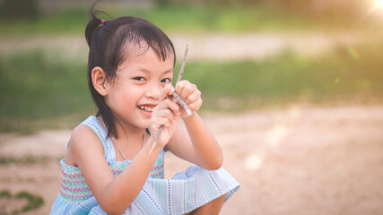 Fototapeta premium Happy little asian girl in blue dress laughs summer on the park