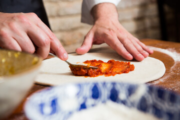 Preparing the dough for a Neapolitan pizza with tomato and cheese.