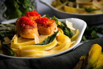 Pan-seared scallops and fettuccine with fresh basil leaves and shaved parmesan. Topped with lumpfish caviar.