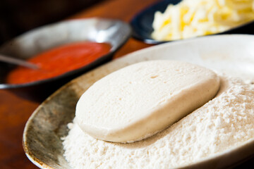 Preparing the dough for a Neapolitan pizza with tomato and cheese.