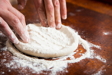Preparing the dough for a Neapolitan pizza with tomato and cheese.