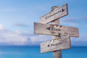 eliminate toxic people text quote on wooden signpost crossroad by the sea - obrazy, fototapety, plakaty