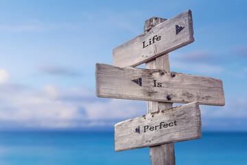 life is perfect text quote on wooden signpost crossroad by the sea