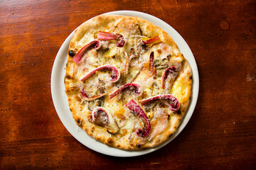 Neapolitan pizza with guanciale, pecorino and radicchio. Classic Italian recipe. Guanciale is an Italian non-smoked cured meat prepared with pork cheeks or cheeks.