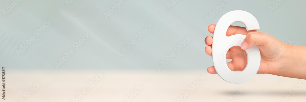 Aufkleber Number six in hand. Hand holding white number 6 on blurred background with copy space. Concept with number six. Birthday 6 years, sixth grade.