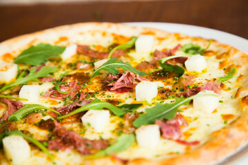 Pizza with arugula meat and cheese. Neapolitan pizza made with mozzarella. Italian recipe.