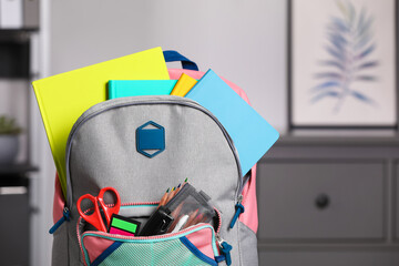 Children's backpack with different school stationery indoors, closeup. Space for text