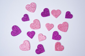 Glittering pink and lilac hearts on white background. Valentines day concept. Womans day. Flat lay.