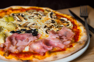 Four Seasons Pizza. Neapolitan pizza with tomato sauce, cheese, ham, mushrooms and vegetables. Authentic Italian recipe.