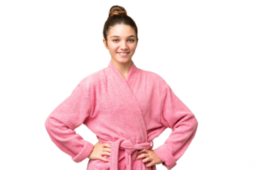 Teenager girl in a bathrobe over isolated chroma key background posing with arms at hip and smiling