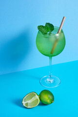 fruit cocktail glass with lime on blue minimalistic background