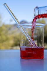 Pouring red liquid in a glass container outside