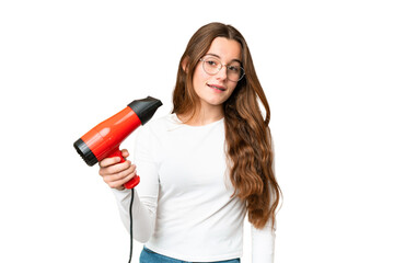 Teenager girl holding a hairdryer over isolated chroma key background with happy expression