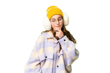 Teenager girl wearing winter muffs over isolated chroma key background looking to the side