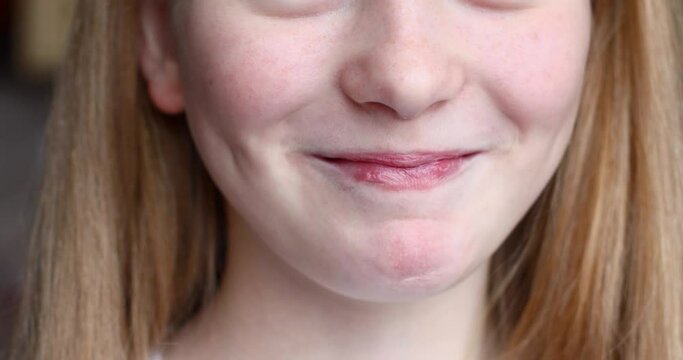 The girl smiles and shows a sad face. Close-up video of a girl's lips