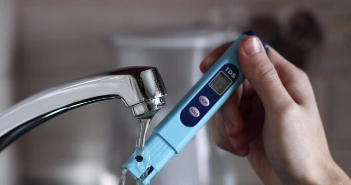 A person brings a tds meter to the tap with running water and checks its quality. The concept of using clean water