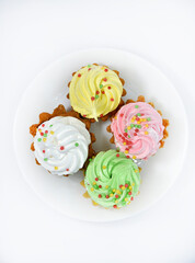 Delicious colorful cakes on a plate. Cream cakes on a white background. Shortbread cakes.