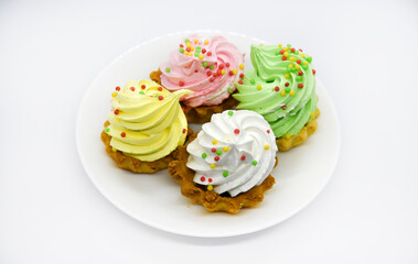 Delicious colorful cakes on a plate. Cream cakes on a white background. Shortbread cakes.