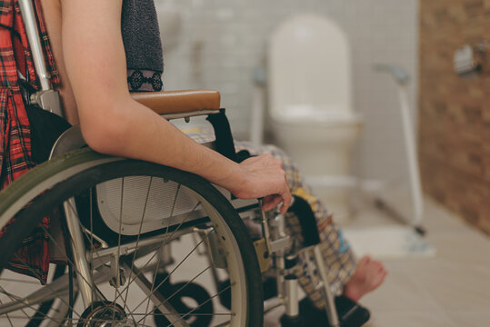 Side view of male teenager in bathroom with wheelchair accessibility in home or hospital or nursery or care facility of person with disability.