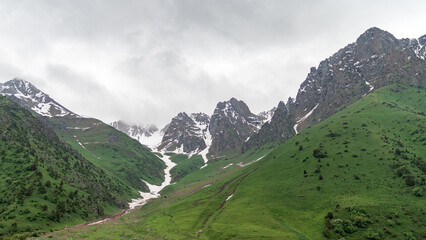 Obraz premium Kyrgyzstan nature green landscape with snow capped mountains. Kyrgyzstan is a landlocked country located in central Asia, known for its rugged, mountainous terrain and verdant grasslands.