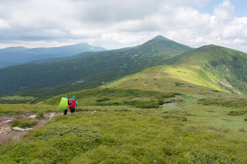 Tourists walk along a mountain path. Panoramic view of Carpathian mountain.