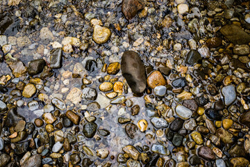 Surface of a clear mountain river with uniform stones bed.