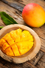 Mango fruit. Ripe Mango fruits over wood background. Close-up of fresh juicy tropical mango ready to eat, healthy sweet dessert, vegan food. Vertical image. 