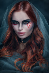 Beautiful witch or vampire woman in a veil. Dark portrait of beauty model with dripping blood make up, Halloween art. Mysterious model girl 