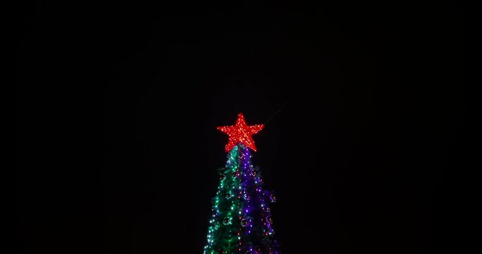 Christmas tree with red star and flashing garland. Stock 4k video.