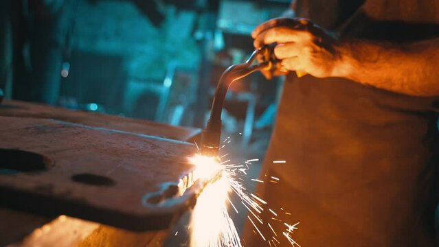 A male locksmith cuts metal with an oxy-fuel torch in a metal cutting workshop