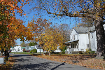 Small town residential street with white clapboard houses and trees with fall color