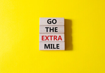 Go the extra mile symbol. Wooden blocks with words Go the extra mile. Beautiful yellow background. Business and Go the extra mile concept. Copy space.