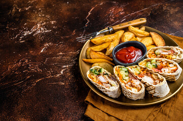 Chicken shawarma durum doner kebab with vegetable salad and french fries. Dark background. Top...