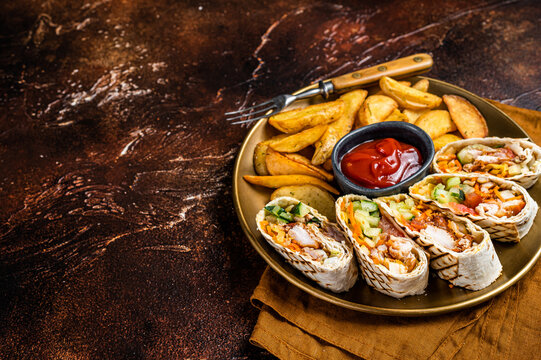 Chicken shawarma durum doner kebab with vegetable salad and french fries. Dark background. Top view. Copy space