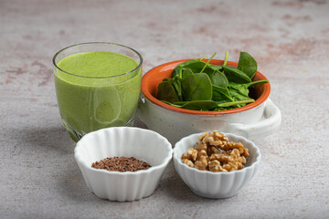 healthy smoothie in a glass with spinach, walnuts, flaxseeds