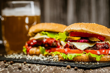 Closeup front view of homemade beef burgers on stone board with glass of beer. Selective focus. 