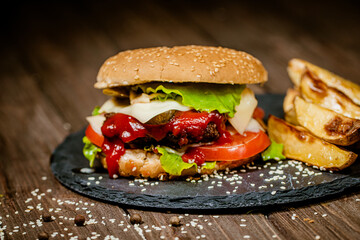 Burger, hamburger with french fries, ketchup, and fresh vegetables on stone board. Homemade cooking