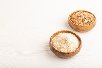 Powdered milk and buckwheat baby food mix, on white wooden, side view, copy space
