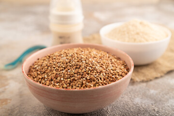 Powdered milk and buckwheat baby food mix, on brown concrete, side view, selective focus