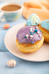Purple and blue glazed donut and cup of coffee on blue wooden, side view, selective focus.