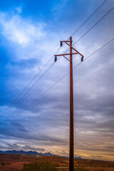 Electricity pylons and cables with stormy clouds over the road in the desert meadow in Bullhead, in Bullhead City, Arizona, USA