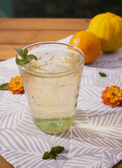 Vaso de bebida fresca en verano con limón y naranja de fondo