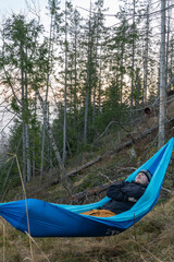 Fototapeta premium Hiker laying in a hammock between trees.