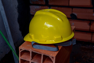 Yellow protective helmet on pile of red bricks